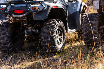 Image showing Close-up tail view of ATV quad bike on dirt country road. Dirty wheel of AWD all-terrain vehicle. Travel and adventure concept.