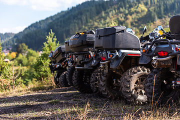 Image showing Close-up tail view of ATV quad bike on dirt country road. Dirty wheel of AWD all-terrain vehicle. Travel and adventure concept.