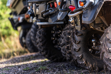 Image showing Close-up tail view of ATV quad bike on dirt country road. Dirty wheel of AWD all-terrain vehicle. Travel and adventure concept.