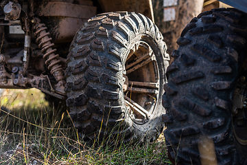 Image showing Close-up tail view of ATV quad bike on dirt country road. Dirty wheel of AWD all-terrain vehicle. Travel and adventure concept.