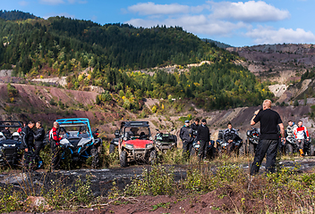 Image showing A group of men on a social gathering are preparing to ride an ATV quad bike. People Ride together on a quad atv on muddy forest roads