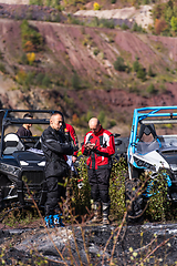 Image showing A man in a forest posing next to a quad and preparing for ride