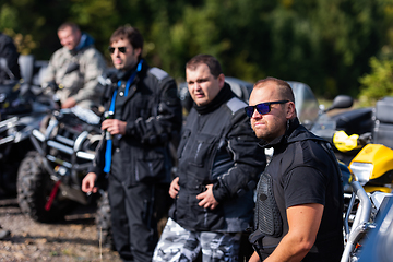 Image showing A group of men on a social gathering are preparing to ride an ATV quad bike. People Ride together on a quad atv on muddy forest roads