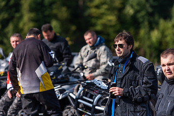 Image showing A group of men on a social gathering are preparing to ride an ATV quad bike. People Ride together on a quad atv on muddy forest roads