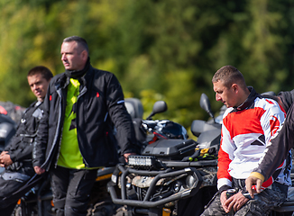 Image showing A group of men on a social gathering are preparing to ride an ATV quad bike. People Ride together on a quad atv on muddy forest roads