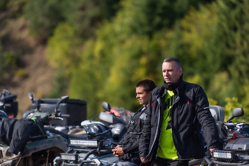 Image showing A group of men on a social gathering are preparing to ride an ATV quad bike. People Ride together on a quad atv on muddy forest roads