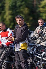 Image showing A group of men on a social gathering are preparing to ride an ATV quad bike. People Ride together on a quad atv on muddy forest roads