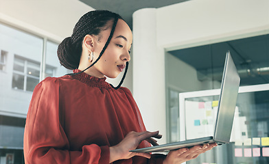 Image showing Woman standing in office with laptop, research and ideas on website for business plan, brainstorming or proposal process. Thinking, typing and businesswoman on computer with online review at startup.