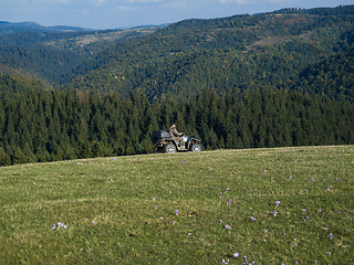 Image showing A man driving a quad ATV motorcycle through beautiful meadow landscapes