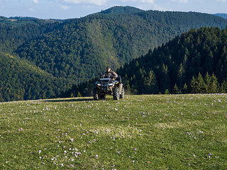 Image showing A man driving a quad ATV motorcycle through beautiful meadow landscapes