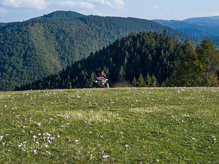 Image showing A man driving a quad ATV motorcycle through beautiful meadow landscapes