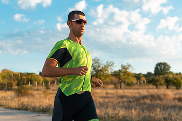 Image showing Triathlete in professional gear running early in the morning, preparing for a marathon, dedication to sport and readiness to take on the challenges of a marathon.