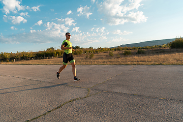 Image showing Triathlete in professional gear running early in the morning, preparing for a marathon, dedication to sport and readiness to take on the challenges of a marathon.