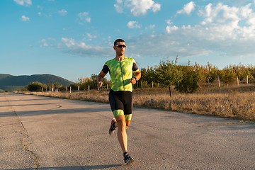 Image showing Triathlete in professional gear running early in the morning, preparing for a marathon, dedication to sport and readiness to take on the challenges of a marathon.