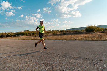 Image showing Triathlete in professional gear running early in the morning, preparing for a marathon, dedication to sport and readiness to take on the challenges of a marathon.