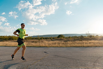 Image showing Triathlete in professional gear running early in the morning, preparing for a marathon, dedication to sport and readiness to take on the challenges of a marathon.