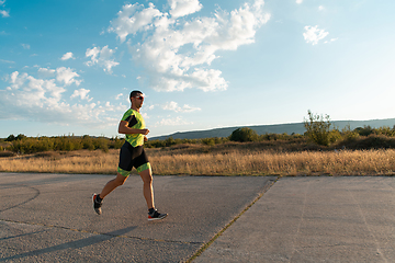 Image showing Triathlete in professional gear running early in the morning, preparing for a marathon, dedication to sport and readiness to take on the challenges of a marathon.