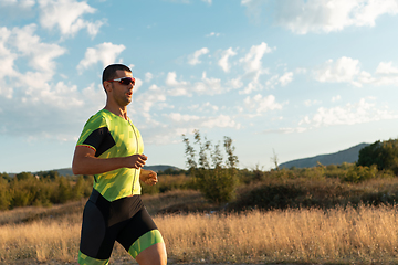 Image showing Triathlete in professional gear running early in the morning, preparing for a marathon, dedication to sport and readiness to take on the challenges of a marathon.