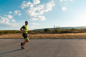 Image showing Triathlete in professional gear running early in the morning, preparing for a marathon, dedication to sport and readiness to take on the challenges of a marathon.