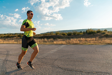 Image showing Triathlete in professional gear running early in the morning, preparing for a marathon, dedication to sport and readiness to take on the challenges of a marathon.