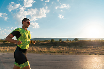 Image showing Triathlete in professional gear running early in the morning, preparing for a marathon, dedication to sport and readiness to take on the challenges of a marathon.