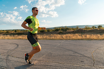 Image showing Triathlete in professional gear running early in the morning, preparing for a marathon, dedication to sport and readiness to take on the challenges of a marathon.