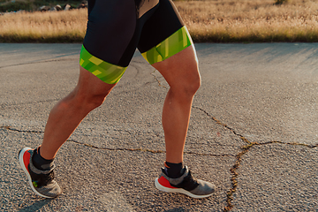 Image showing Closeup of muscular legs of a triathlete in professional equipment running early in the morning, preparing for a marathon, dedication to sports and readiness for marathon challenges