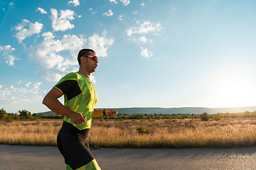 Image showing Triathlete in professional gear running early in the morning, preparing for a marathon, dedication to sport and readiness to take on the challenges of a marathon.