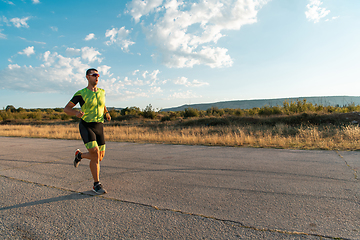 Image showing Triathlete in professional gear running early in the morning, preparing for a marathon, dedication to sport and readiness to take on the challenges of a marathon.