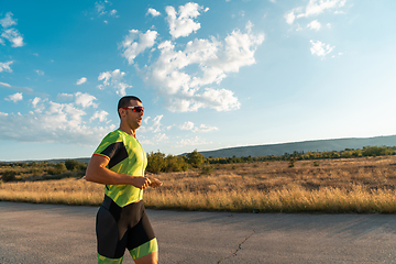 Image showing Triathlete in professional gear running early in the morning, preparing for a marathon, dedication to sport and readiness to take on the challenges of a marathon.