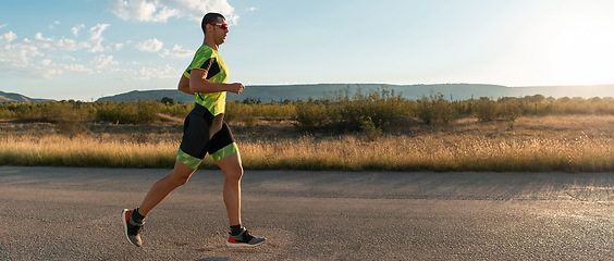 Image showing Triathlete in professional gear running early in the morning, preparing for a marathon, dedication to sport and readiness to take on the challenges of a marathon.