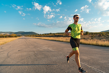 Image showing Triathlete in professional gear running early in the morning, preparing for a marathon, dedication to sport and readiness to take on the challenges of a marathon.