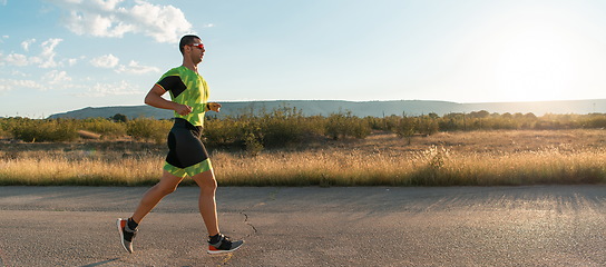 Image showing Triathlete in professional gear running early in the morning, preparing for a marathon, dedication to sport and readiness to take on the challenges of a marathon.