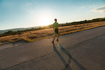 Image showing Triathlete in professional gear running early in the morning, preparing for a marathon, dedication to sport and readiness to take on the challenges of a marathon.