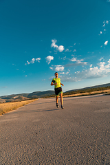 Image showing Triathlete in professional gear running early in the morning, preparing for a marathon, dedication to sport and readiness to take on the challenges of a marathon.