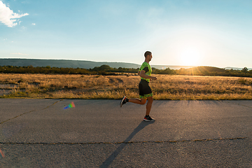 Image showing Triathlete in professional gear running early in the morning, preparing for a marathon, dedication to sport and readiness to take on the challenges of a marathon.