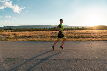 Image showing Triathlete in professional gear running early in the morning, preparing for a marathon, dedication to sport and readiness to take on the challenges of a marathon.