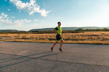 Image showing Triathlete in professional gear running early in the morning, preparing for a marathon, dedication to sport and readiness to take on the challenges of a marathon.