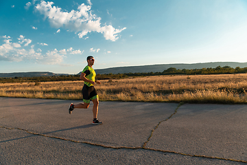 Image showing Triathlete in professional gear running early in the morning, preparing for a marathon, dedication to sport and readiness to take on the challenges of a marathon.