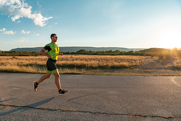 Image showing Triathlete in professional gear running early in the morning, preparing for a marathon, dedication to sport and readiness to take on the challenges of a marathon.