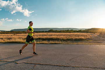 Image showing Triathlete in professional gear running early in the morning, preparing for a marathon, dedication to sport and readiness to take on the challenges of a marathon.