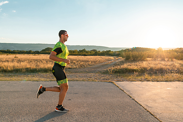 Image showing Triathlete in professional gear running early in the morning, preparing for a marathon, dedication to sport and readiness to take on the challenges of a marathon.