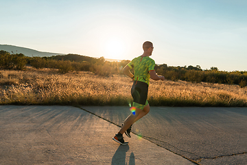 Image showing Triathlete in professional gear running early in the morning, preparing for a marathon, dedication to sport and readiness to take on the challenges of a marathon.