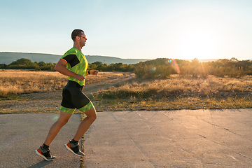 Image showing Triathlete in professional gear running early in the morning, preparing for a marathon, dedication to sport and readiness to take on the challenges of a marathon.