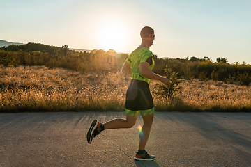 Image showing Triathlete in professional gear running early in the morning, preparing for a marathon, dedication to sport and readiness to take on the challenges of a marathon.