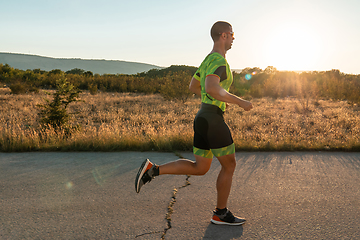 Image showing Triathlete in professional gear running early in the morning, preparing for a marathon, dedication to sport and readiness to take on the challenges of a marathon.