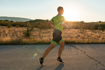 Image showing Triathlete in professional gear running early in the morning, preparing for a marathon, dedication to sport and readiness to take on the challenges of a marathon.