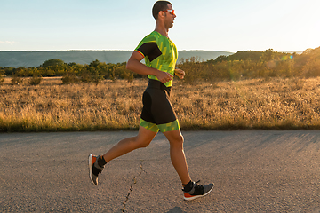 Image showing Triathlete in professional gear running early in the morning, preparing for a marathon, dedication to sport and readiness to take on the challenges of a marathon.