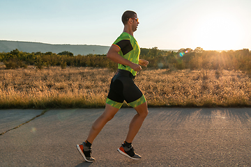 Image showing Triathlete in professional gear running early in the morning, preparing for a marathon, dedication to sport and readiness to take on the challenges of a marathon.