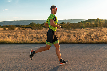 Image showing Triathlete in professional gear running early in the morning, preparing for a marathon, dedication to sport and readiness to take on the challenges of a marathon.